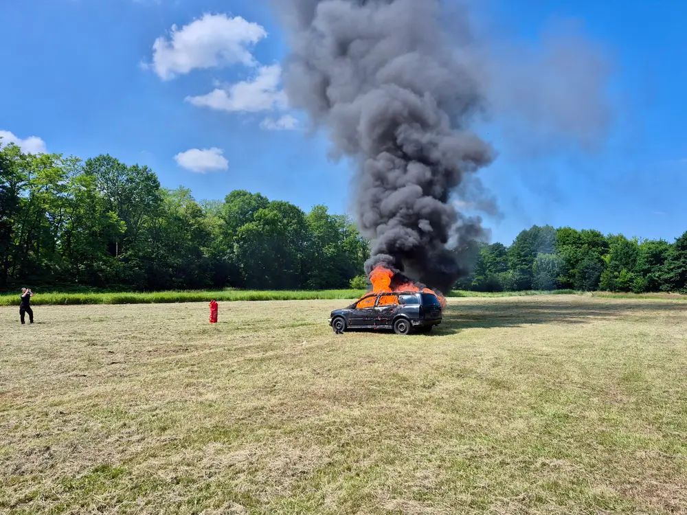 Burning car with a column of black smoke before the fire blanket is applied