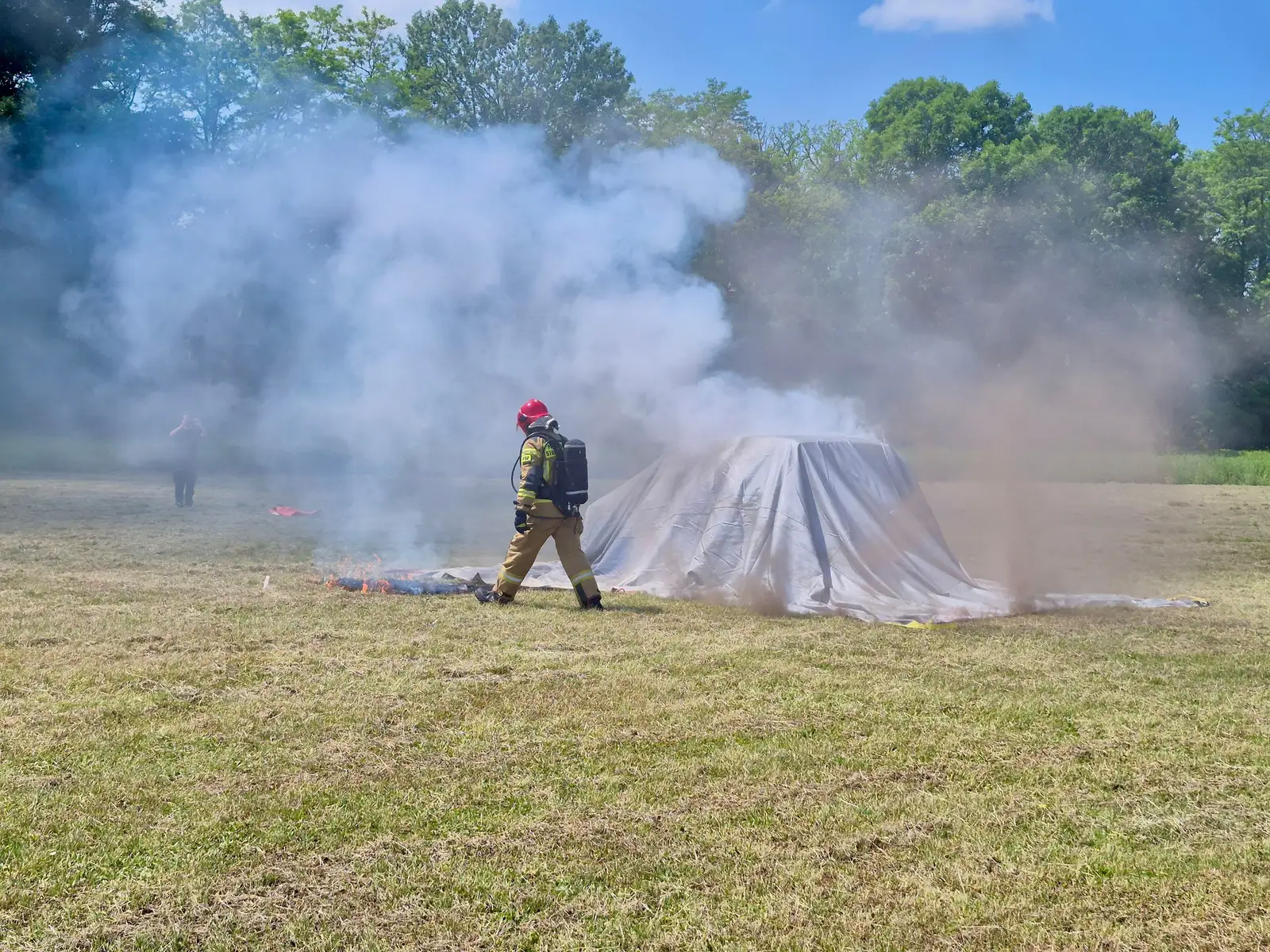 Firefighter next to a car covered with the WINGS fire blanket during a firefighting demonstration