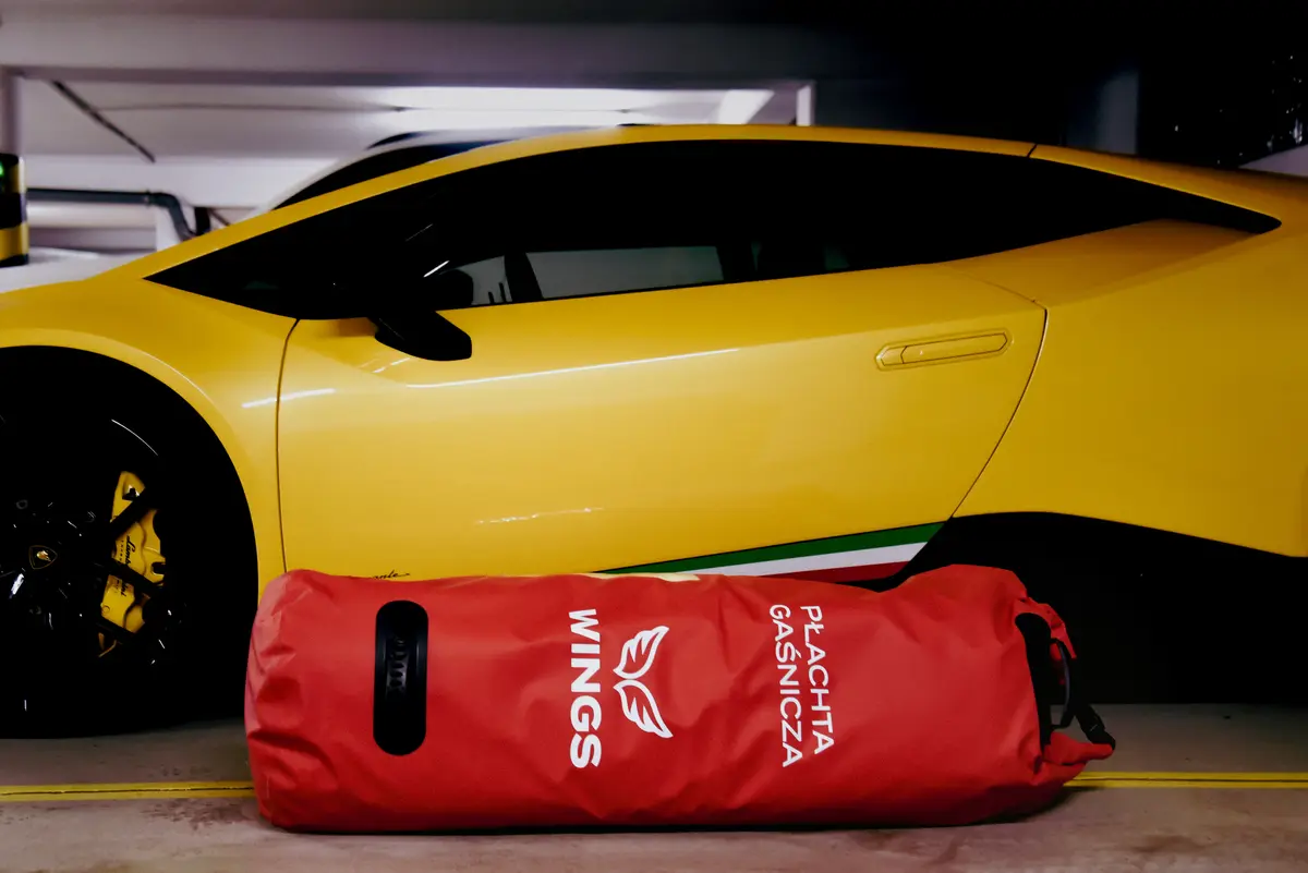 Red WINGS fire blanket bag next to a yellow sports car